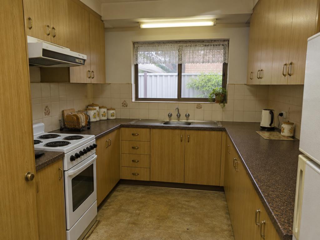 Kitchen before renovation with honey-oak laminate cupboards and dark benchtops